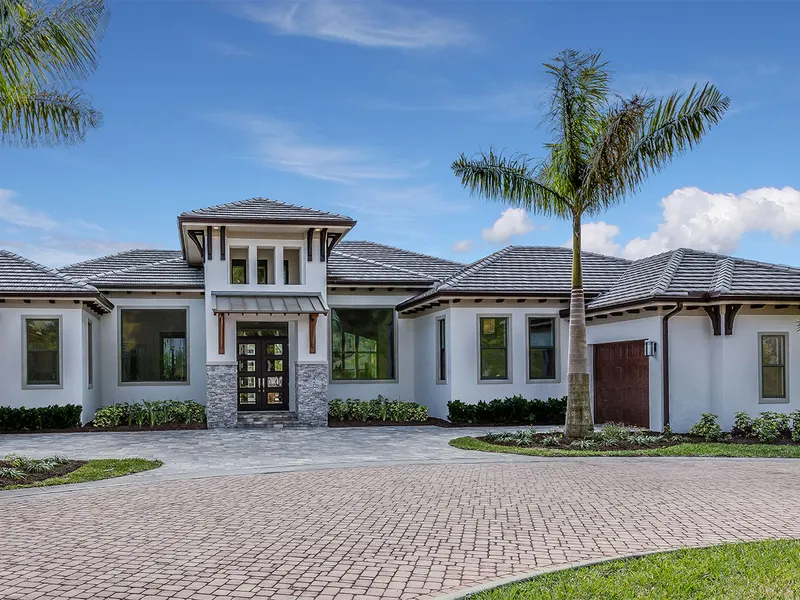 Front exterior of a single-story stucco home with single hung windows and a paver driveway