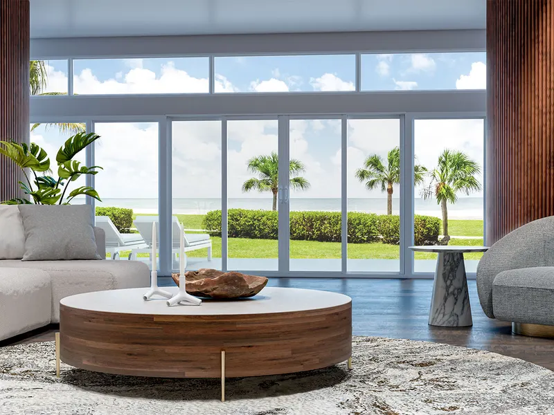 Living room with a wide white bi-parting sliding glass door and transoms facing palm trees