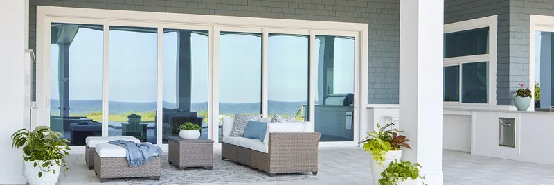 Covered porch with outdoor seating in front of a wall of white sliding glass doors (wide banner crop)
