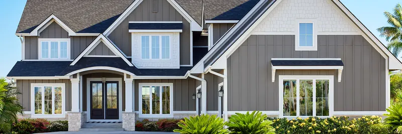 Two-story gray-sided home exterior with white-framed windows (wide banner crop)
