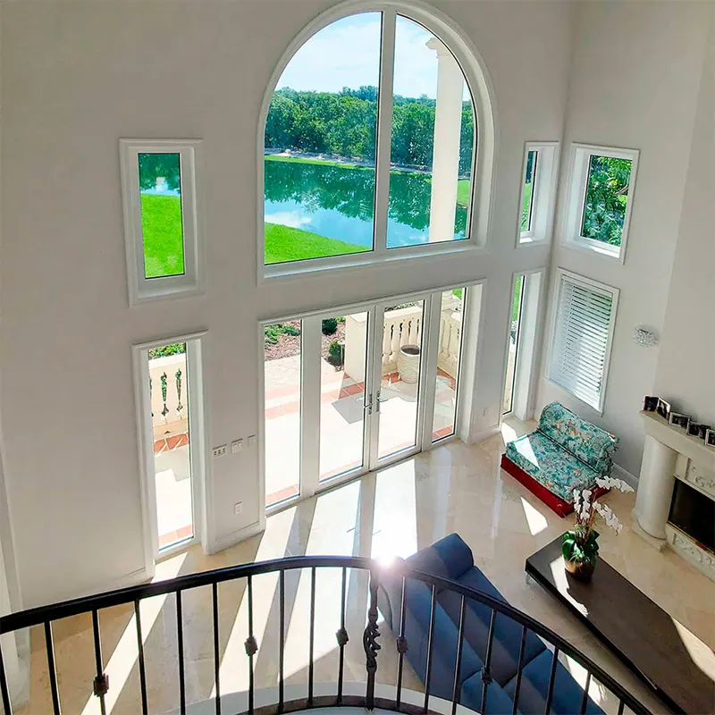 Two-story great room with an arched window, transoms and French doors overlooking a lake