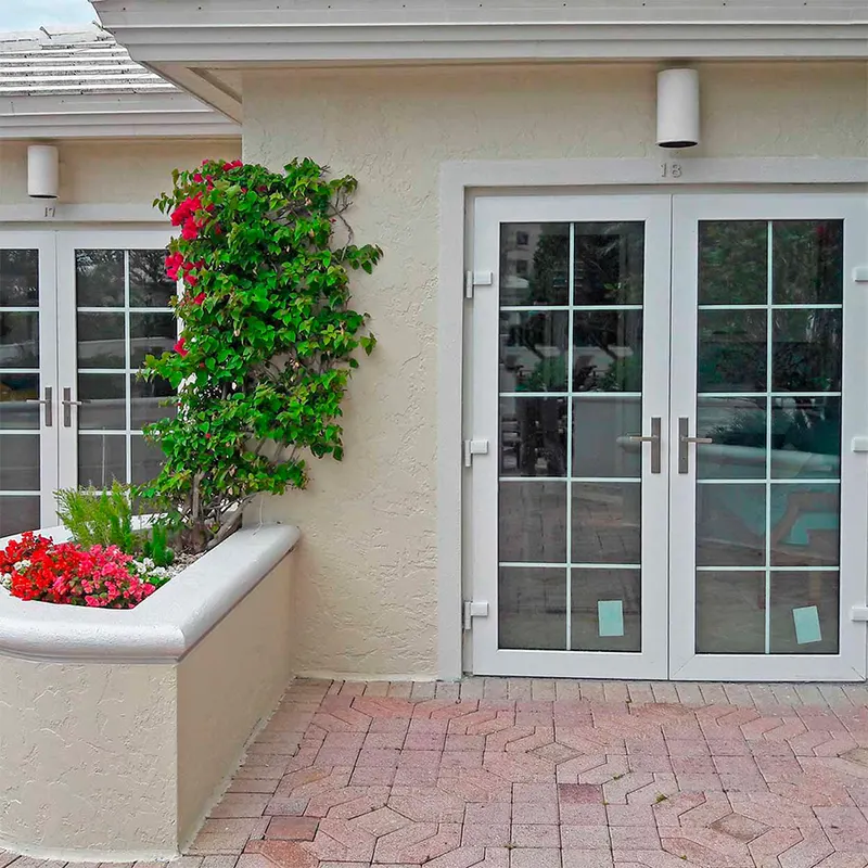 White French doors with grids on a home entry courtyard with flowers