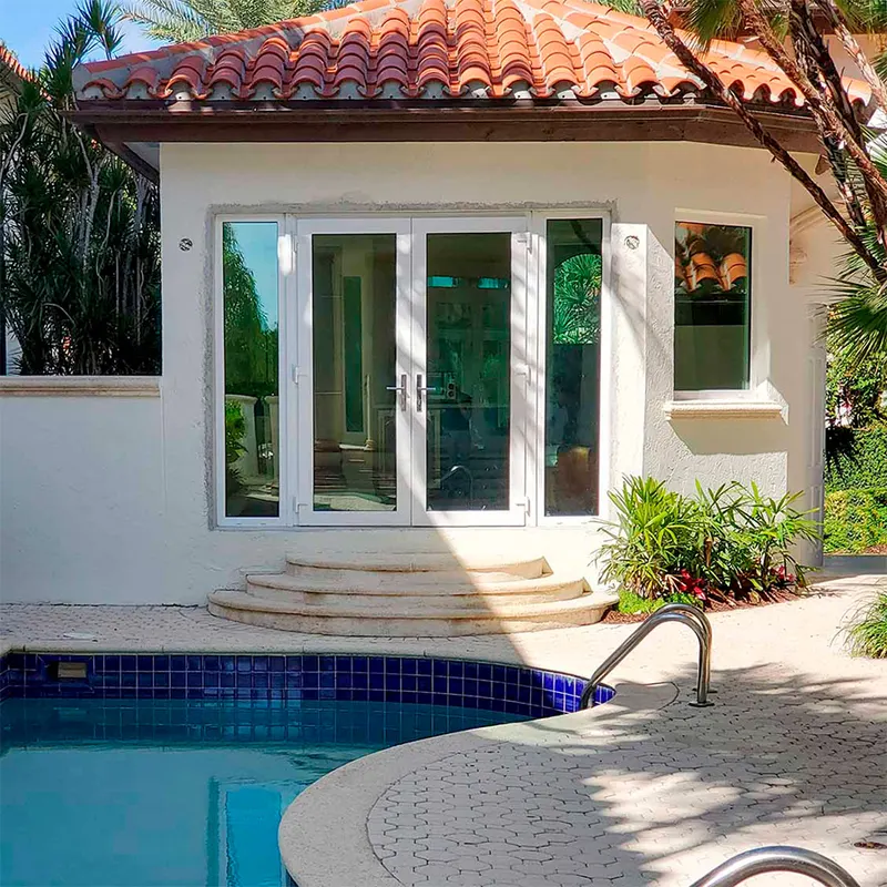 Pool house with white French doors and windows behind a pool