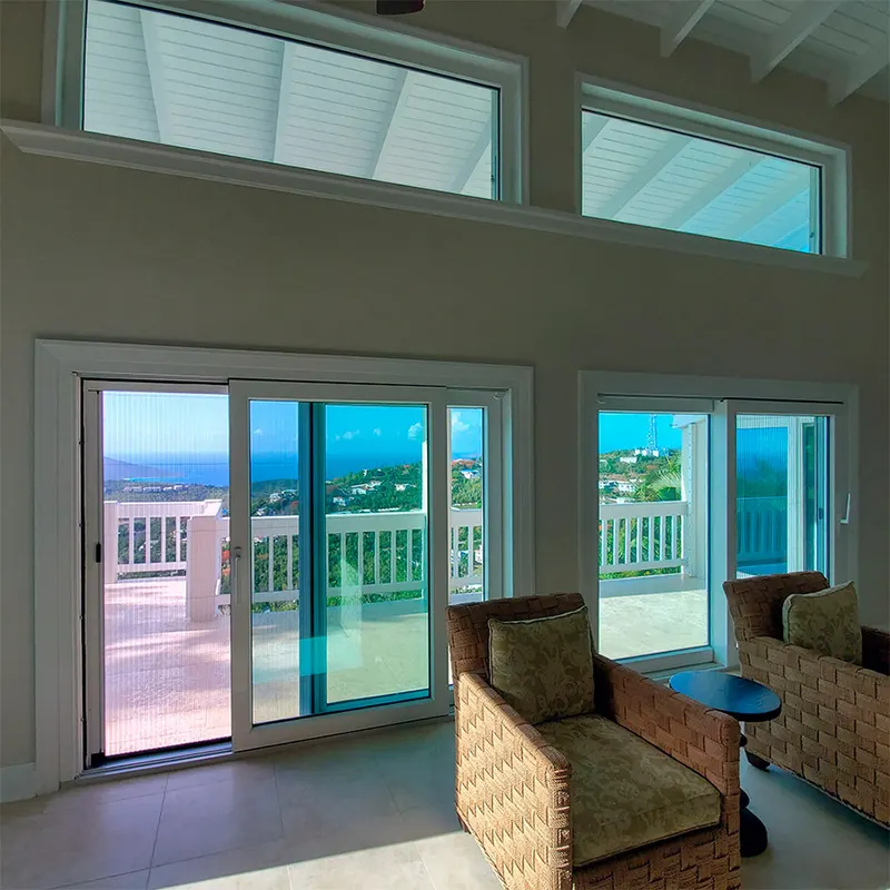 Living room with white transom windows above sliding glass doors facing an ocean view