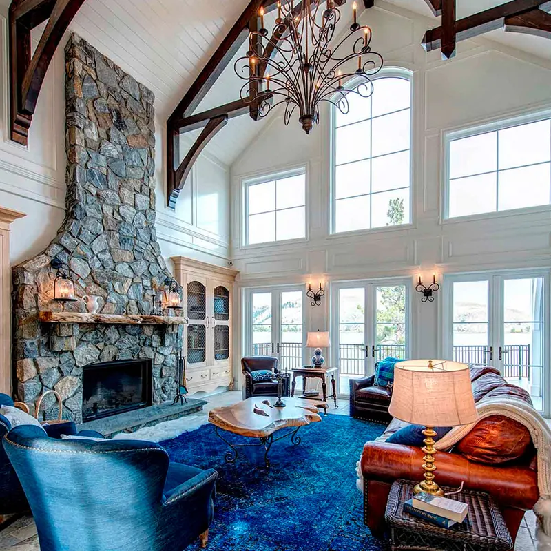 Vaulted living room with a stone fireplace and rows of white-framed windows
