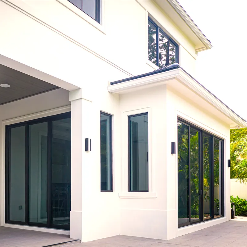 White house with a covered patio and tall dark-framed glass doors and windows at the corner