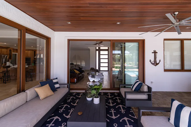 Covered patio with a wood ceiling and outdoor sofa set in front of wood-tone sliding glass doors