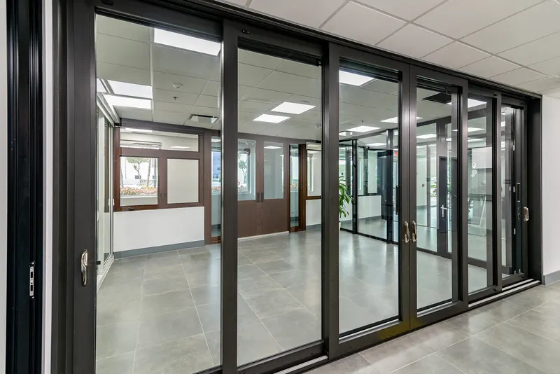 Dark bronze multi-panel sliding glass door installed across a showroom wall