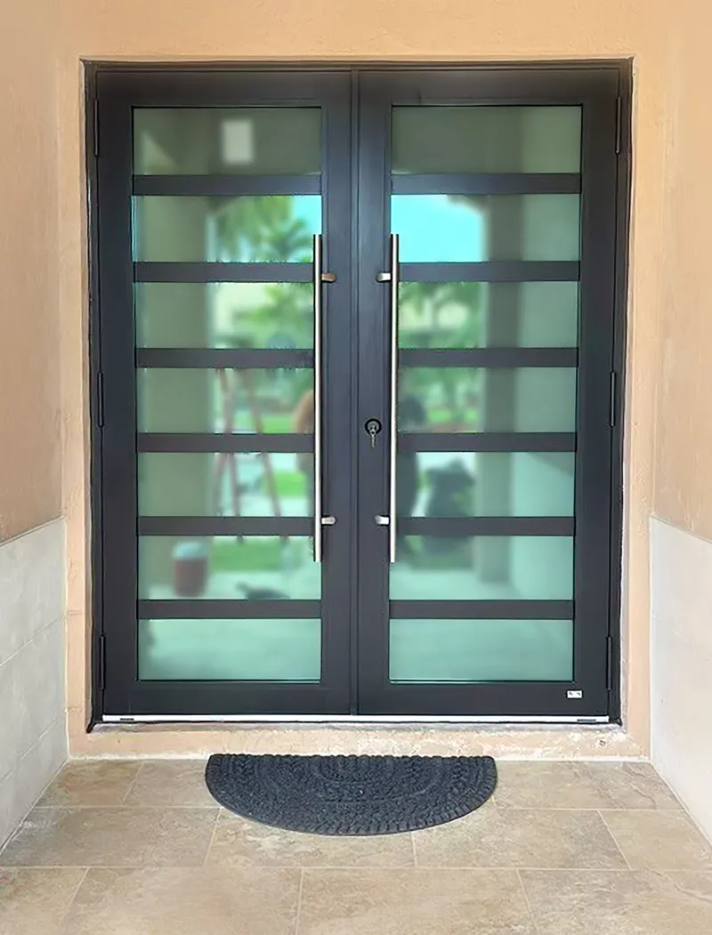Black double swing doors with horizontal glass lites and long pull handles set into a stucco entry