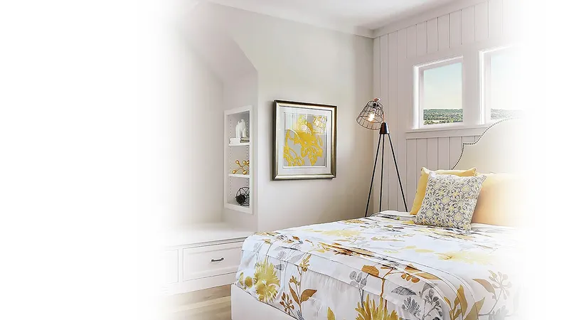 Bright bedroom with a floral bedspread, side lamp and window in a white wall