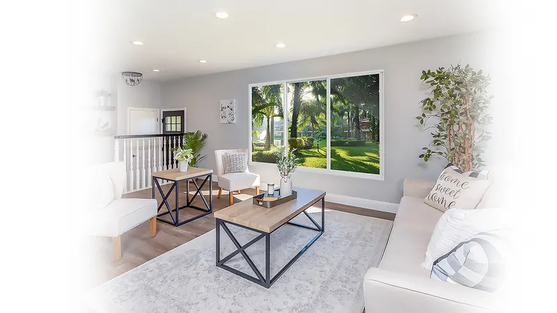 Living room with a coffee table and plants in front of a wide window looking onto trees