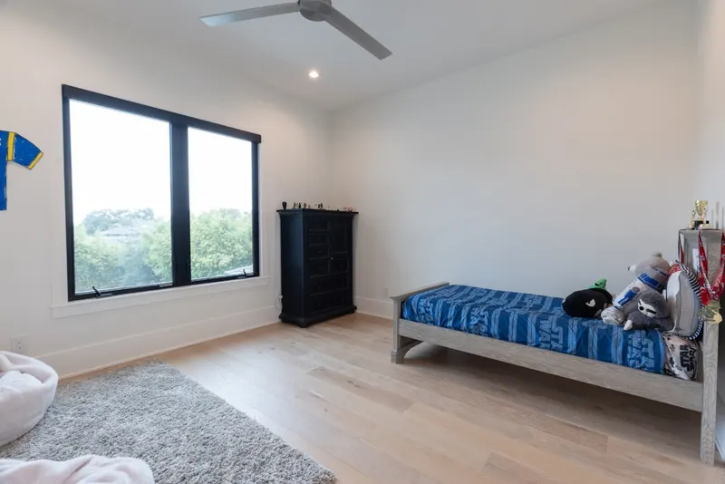 Black-framed casement windows in a white bedroom with a single bed and dresser