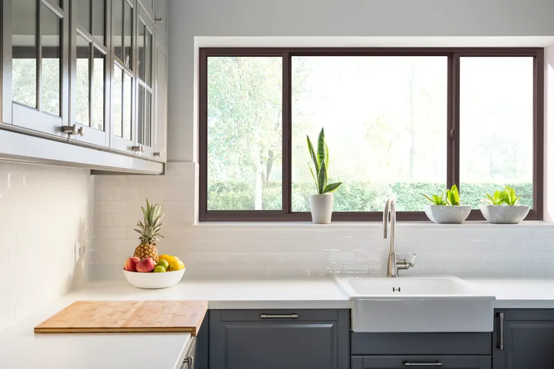 Bronze-framed horizontal roller window above a white farmhouse kitchen sink