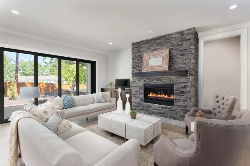Living room with stone fireplace and a wall of black-framed sliding glass doors