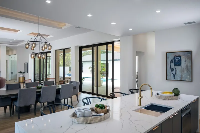 Open great room and kitchen with black-framed sliding glass doors along the back wall