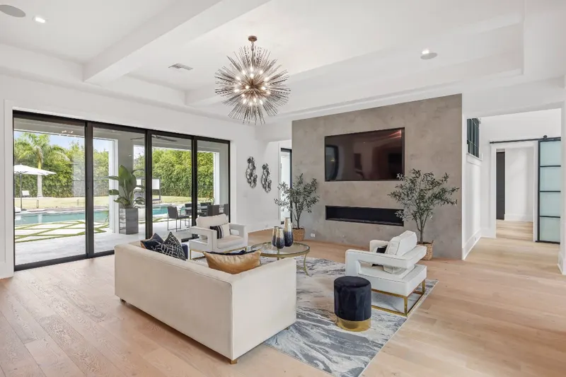Living room with a fireplace wall and black-framed sliding glass doors facing a pool