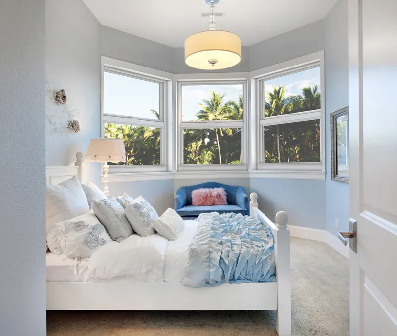 Bright bedroom with a bay of white single hung windows above a cushioned window seat