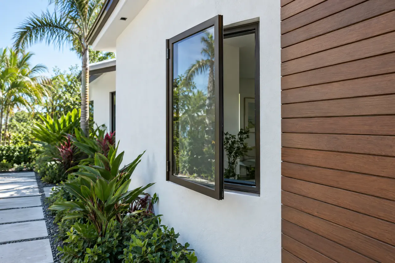Bronze casement window swung outward on side hinges beside a garden path