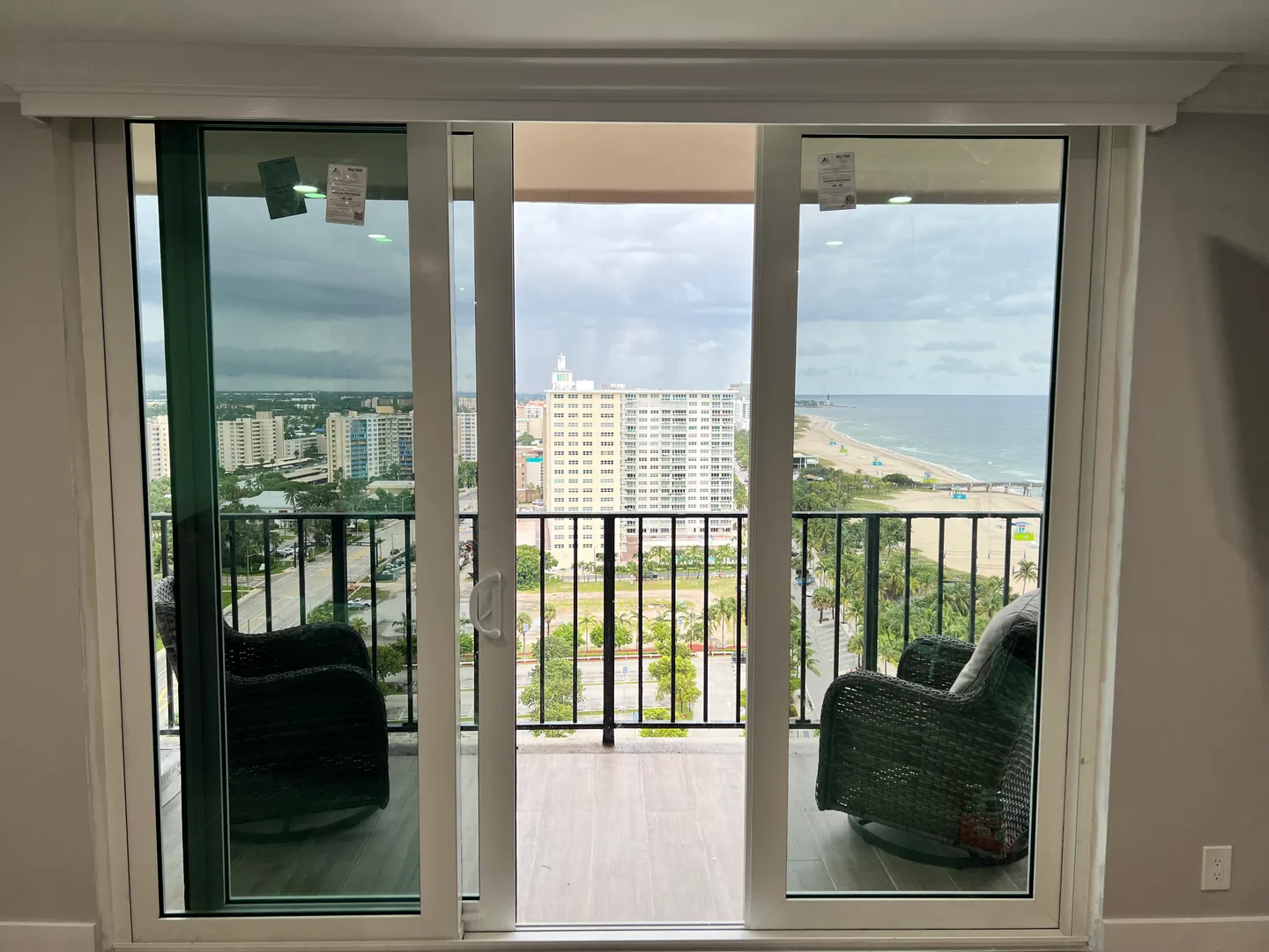 An open white-framed sliding door connecting a room to an ocean-view balcony.