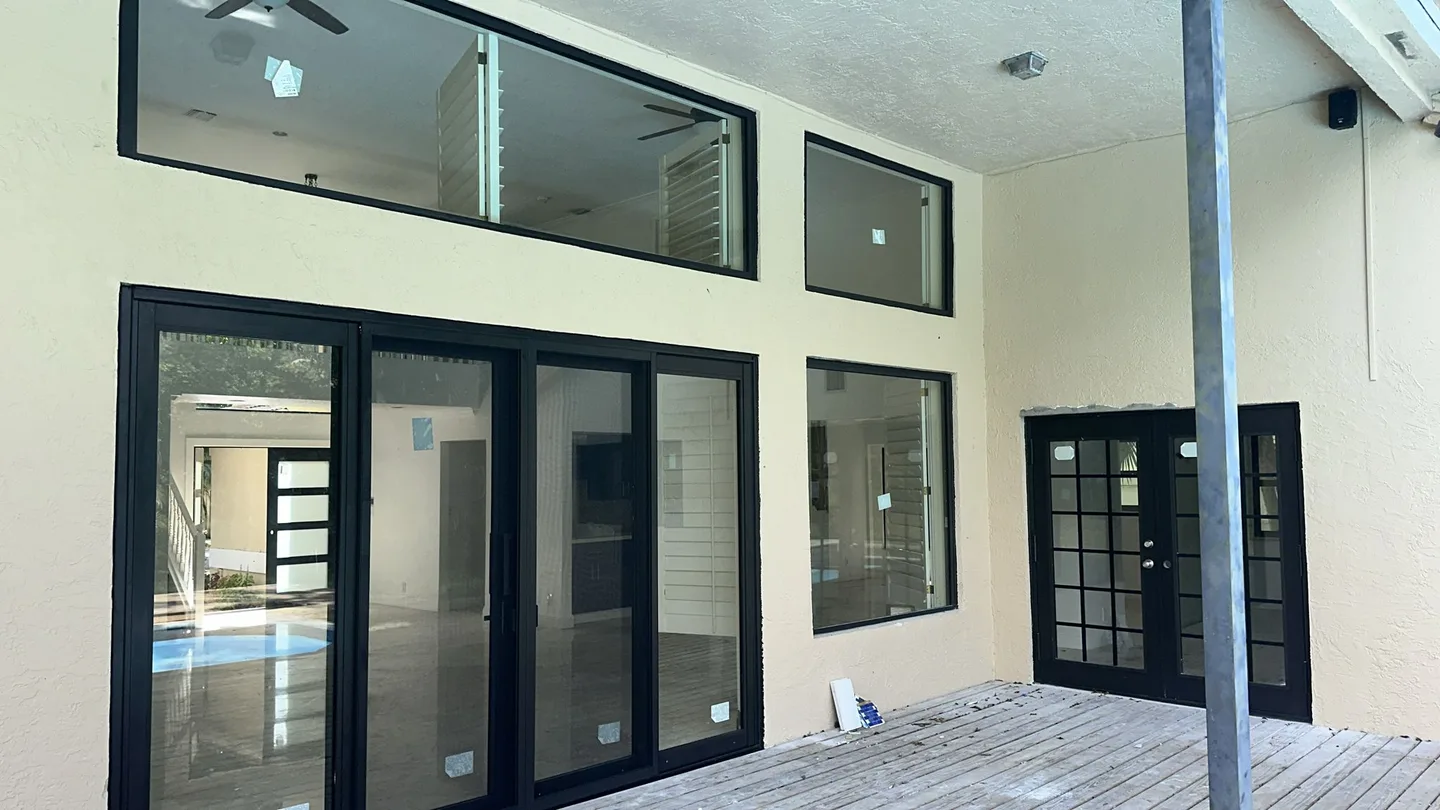 Dark-framed sliding doors, picture windows and transoms along a covered patio.